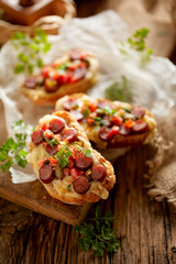 Bruschetta with cheese and sausage sprinkled with herbs, close up view