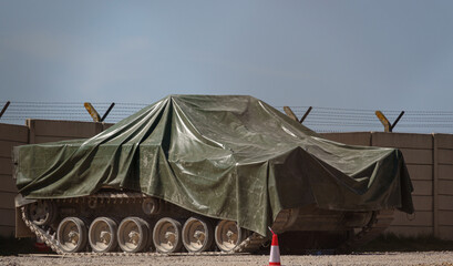 British army Warrior FV510 light infantry fighting vehicle under tarpaulin awaiting maintenance and...