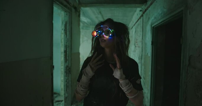 A robot girl from the future with artificial intelligence and colored glowing glasses wanders through an abandoned building sees strange things smiles to herself