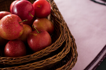 Red and fresh plums in a basket on a black table 
