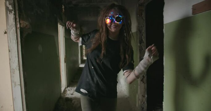 A girl from the future the newest robot from another planet with colored glasses walks on an abandoned building after the apocalypse dances smiles draws with her hands sees different things