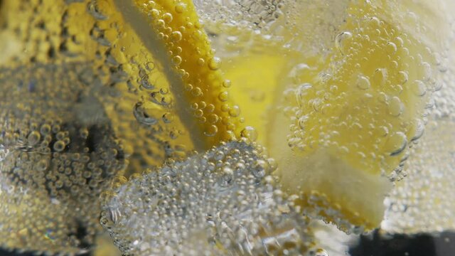 Close up of a refreshing drink with bubbles interacting with ice and Lemon. Lemon drink with ice. Refreshing soft drink Lemon and sparkling water with ice.