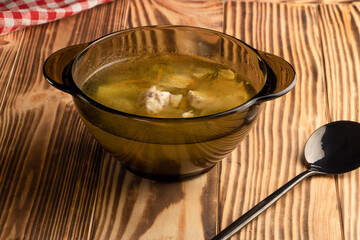 homemade chicken soup in a glass plate stands on a wooden table. Portion of lunch. The concept of proper nutrition and healthy eating. High quality photo