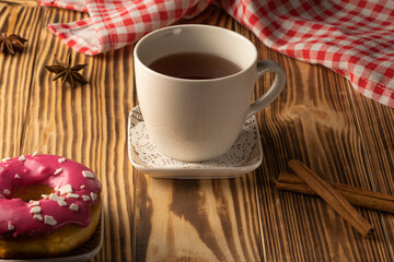 a cup of tea on a wooden table . biscuits , cookie sprinkled with peanuts. Tea party concept. Cinnamon sticks on burnt wooden background. High quality photo