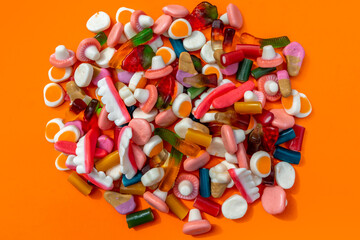 A group of colourful candies against an orange background 
