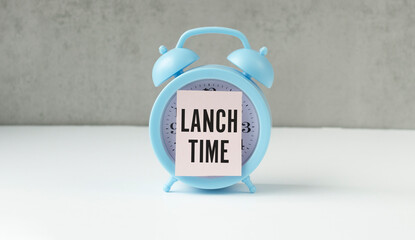 Notepad with LAUNCH TIME message, business concept image on alarm clock with gray background.
