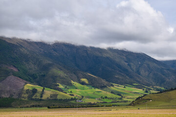 Fototapeta na wymiar Extenso campo verde y grandes montañas en una fría mañana