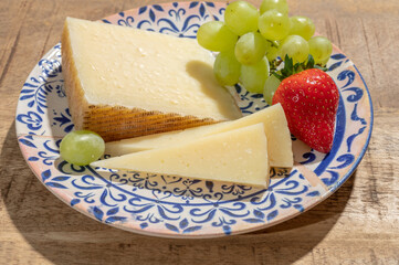 Cheese collection, piece of spanisch hard manchego cheese made in La Mancha region from sheep milk with green grapes and red strawberry