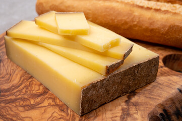 French food -  piece of cheese comte made from cow milk in region Franche-Comte in France and fresh baked baguette bread.