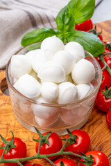 Italian tricolore, small balls of fresh white soft Italian mozzarella cheese, ripe red cherry tomatoes and fresh green basil herb, ready for making caprese salad