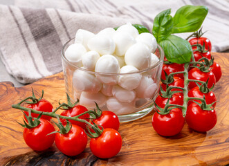Italian tricolore, small balls of fresh white soft Italian mozzarella cheese, ripe red cherry tomatoes and fresh green basil herb, ready for making caprese salad