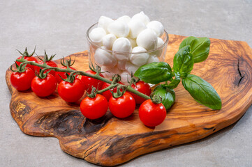 Italian tricolore, small balls of fresh white soft Italian mozzarella cheese, ripe red cherry tomatoes and fresh green basil herb, ready for making caprese salad