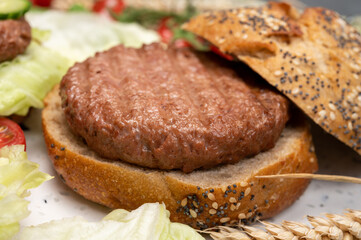 Making tasty vegetarian vegan hamburger from plant based soya beans burger, organic bun with seeds and fresh vegetables