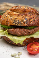 Making tasty vegetarian vegan hamburger from plant based soya beans burger, organic bun with seeds and fresh vegetables