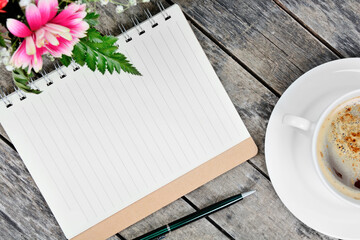 Empty notebook with pen, coffee cup and flowers on table