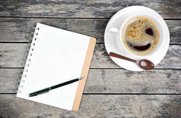 Empty notepad with pen and coffee cup on table