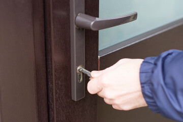 Handyman checks the door lock with a key in front door. Checking lock for operability.