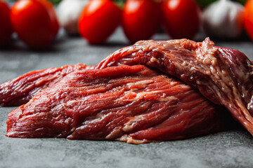 Two fresh flank steaks on a tomato background. - obrazy, fototapety, plakaty