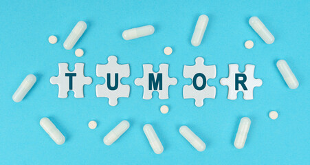 On a blue background, there are pills and puzzles with the inscription - TUMOR