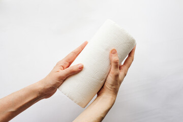 Female hands that hold rolls of paper towels, napkins on a white background. White on white, pulp,...