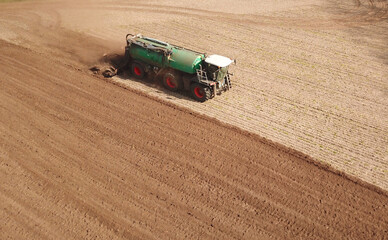 Obraz premium Gülle-Selbstfahrer bringt Gülle auf einem Acker aus, industrielle Landwirtschaft, Selbstfahrer, Gülletonne, Vogelperspektive