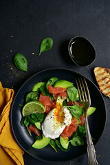 Avocado and baby spinach salad with salted salmon and poached egg. Top view with copy space.