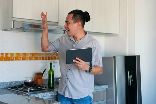 Latin man happy in the kitchen using a tablet - Powered by Adobe