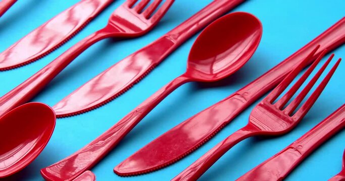Single use red plastic cutlery on a blue background. Concept: Ban single use plastic.