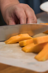 sharp knife chopping through a pile of canteloupe chunks