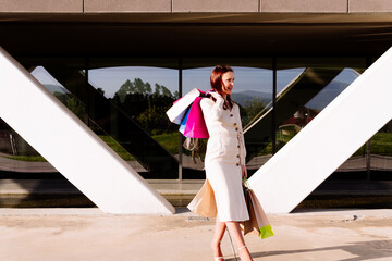 Attractive beautiful young adult woman shopping in shopping area walking with colorful shopping bags. happy shopping concept in summer or spring