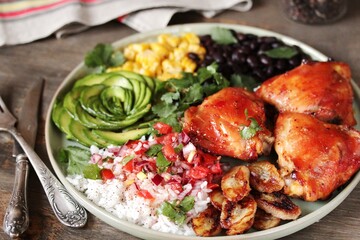 latin american food bowl - rose avocado, rice, salsa, fried banana, spiced baked chicken thighs, black beans, corn, cilantro.