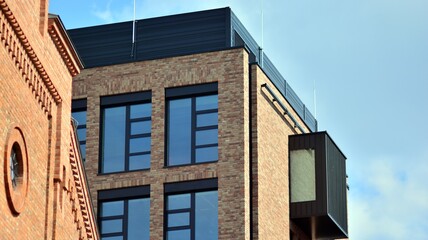 Modern brick and glass facade of the office building.  A contrasting combination of sky and brick texture on a building. Architectural facade of a red brick building..