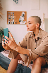 Girl with short haircut sitting at the mattress and doing selfie