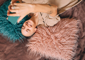 Girl with short haircut laying at the fur and posing to the selfie