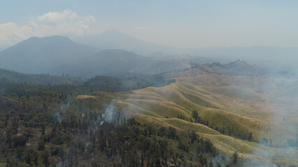 aerial view forest fire smoke on slopes hills. wild fire in tropical forest, Java Indonesia. natural disaster fire in Southeast Asia