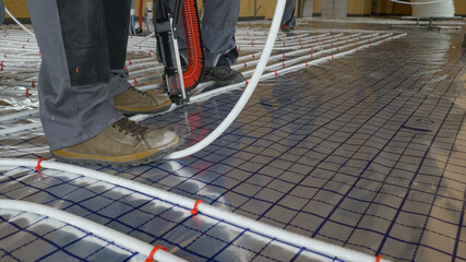 CLOSE UP: Contractors lay white plastic tubing while installing ground heating.