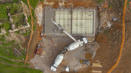 TOP DOWN: Workers pouring concrete from a truck, creating the house foundation.