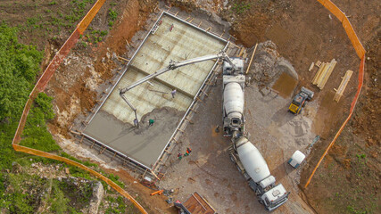 DRONE: Construction site crew pump cement onto the base for modern house.
