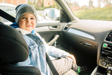 Little boy sitting in the front of the car. Child alone in the car. Child sits on a child seat 