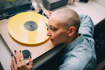 Woman with short hair sitting near her vinyl music player and feeling pleasure