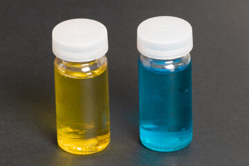 Two small transparent containers with yellow and blue liquid