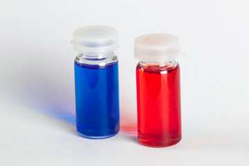 Two small transparent containers with red and blue liquid