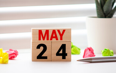 White block calendar present date 24 and month May on wood background