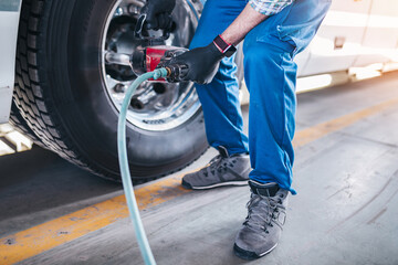 Mechanic repairing flat tire at bus. Vehicle repair service.