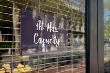 At Max Capacity sign at the entrance to a retail store when maximum occupancy is reached during the coronavirus pandemic.
