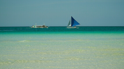 Seascape: tropical beach and sailing yacht in crystal clear turquoise water. Summer and travel...