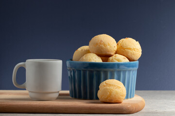 Cheese bread (Pão de queijo) on a blue bowl and a cup of coffee.