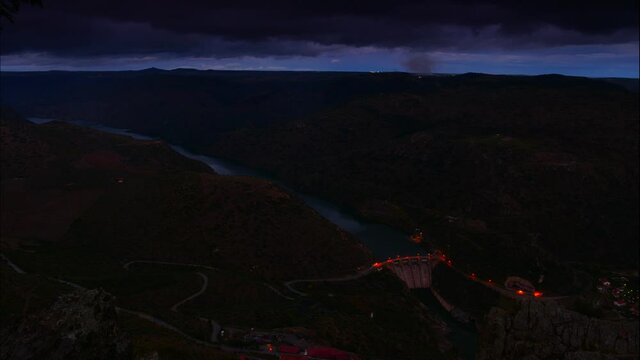 Time lapse of nightfall over mountain and Douro river with spanish Saucelle Dam. Border between Portugal and Spain. National Parks. View from portuguese Penedo Durao lookout.
