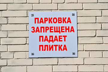 parking prohibited. falling tiles as warning text on brick stone wall on russian language, security warning diversity