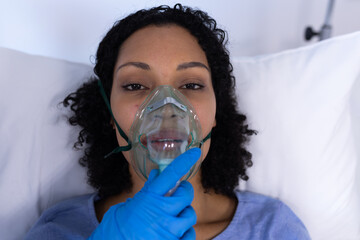 Portrait of african american female patient with oxygen ventilator in hospital bed